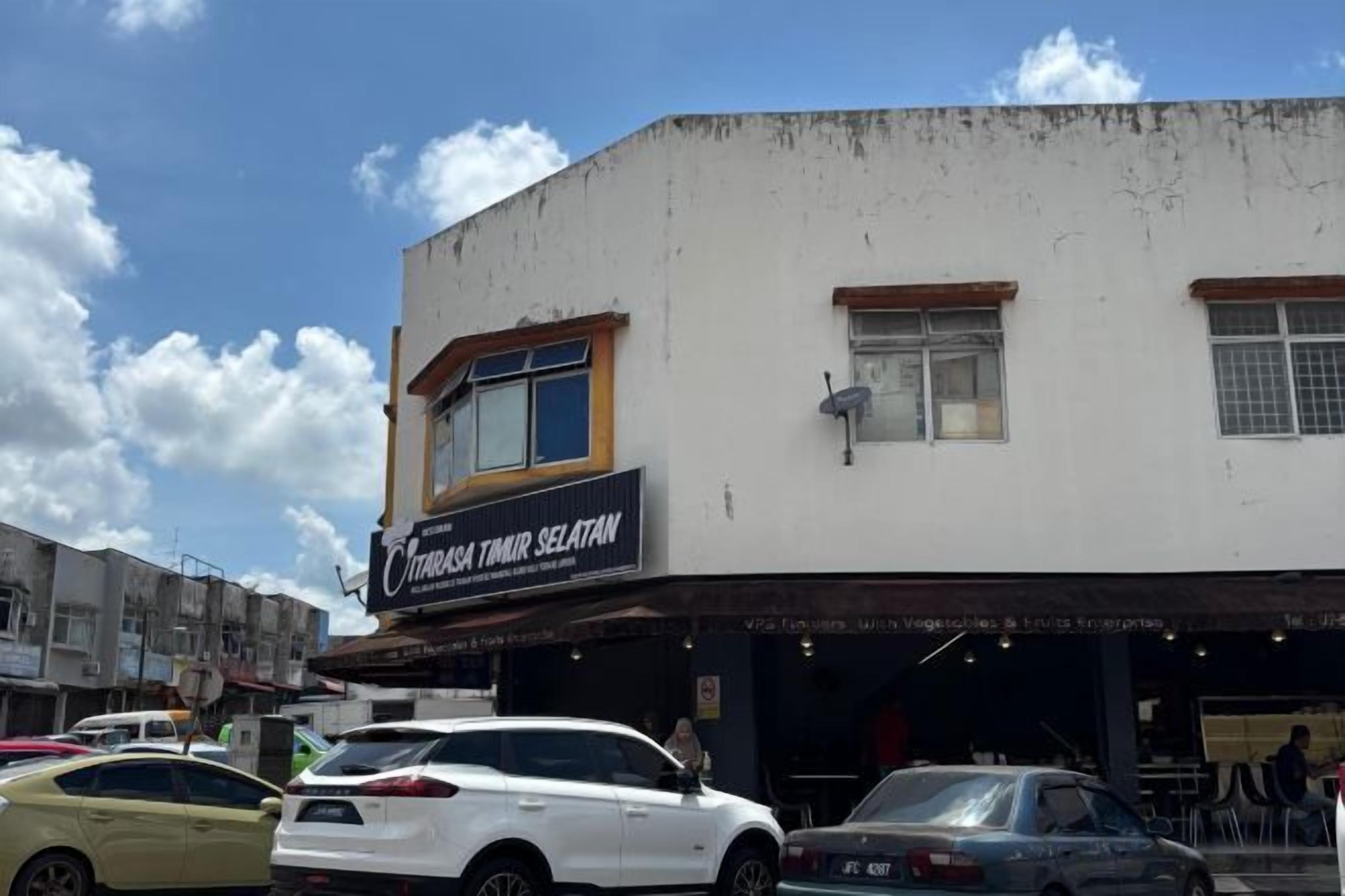A building with a sign that reads 'Cintai Tawar Selatan' and multiple parked cars in front.
