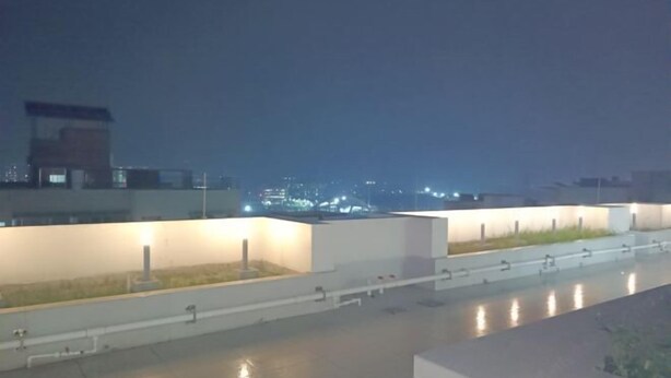A rooftop terrace with a view of the cityscape at night.