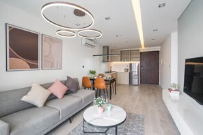Ein modernes Wohnzimmer mit grauem Sofa, einem runden Couchtisch und einem Essbereich mit Stühlen und Tisch.