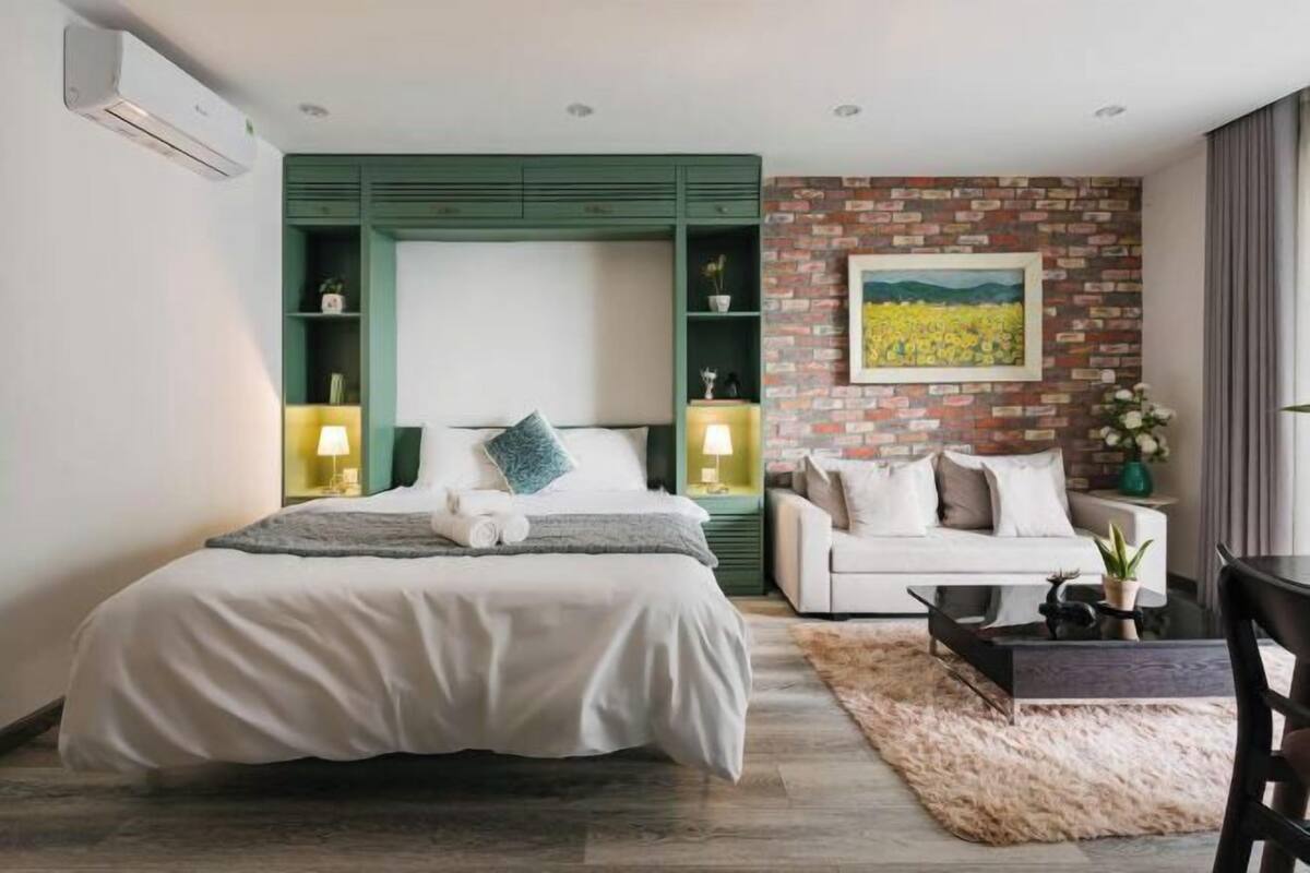 Ein modernes Schlafzimmer mit Bett, Sofa, Couchtisch und einer Wand mit Ziegelmuster.