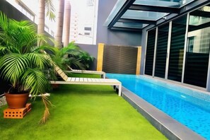 A pool area with artificial grass, a lounge chair, and potted plants. - JJH Serviced Apartments Near Serangoon MRT (Singapore)
