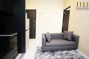 A modern living room with a grey sofa, a black cabinet, and a patterned rug. - JJH Serviced Apartments Near Serangoon MRT (Singapore)