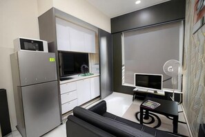 A compact kitchen with a refrigerator, microwave, and stove, a dining area with a table and chairs, and a large window with blinds. - JJH Serviced Apartments Near Serangoon MRT (Singapore)