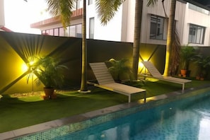 A swimming pool with two lounge chairs and potted plants. - JJH Serviced Apartments Near Serangoon MRT (Singapore)