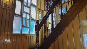 Un escalier en bois avec une rampe et une fenêtre à vitrage dépoli.