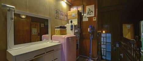 A compact room with a kitchenette, a mirror, a small sink, and a door leading to another room.
