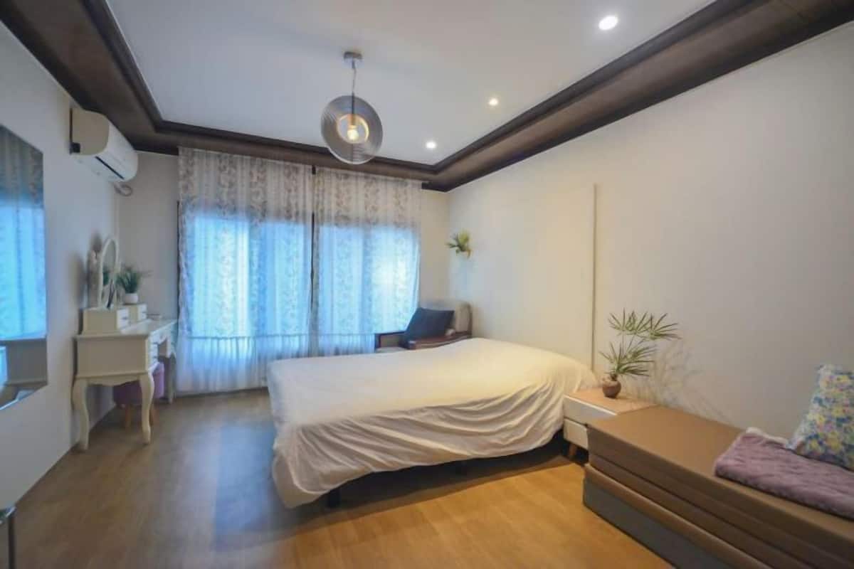 Un dormitorio con cama, mesita de noche y ventana con cortinas.