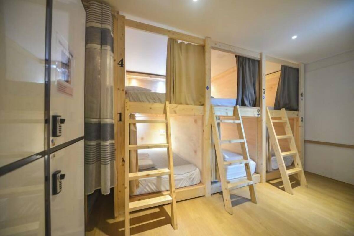 Una habitación con literas, escaleras de madera y un refrigerador.