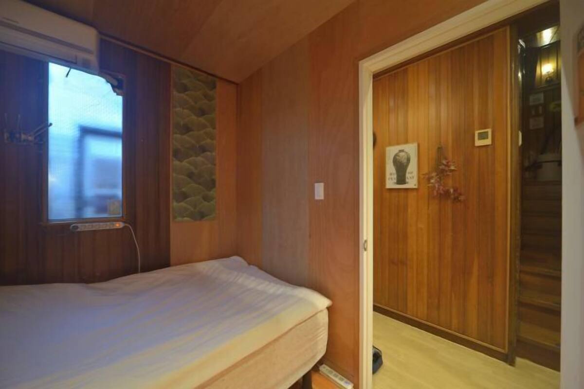 Una habitación con paredes de madera, una cama, un muro decorativo de piedra y una puerta de madera con un cuadro.