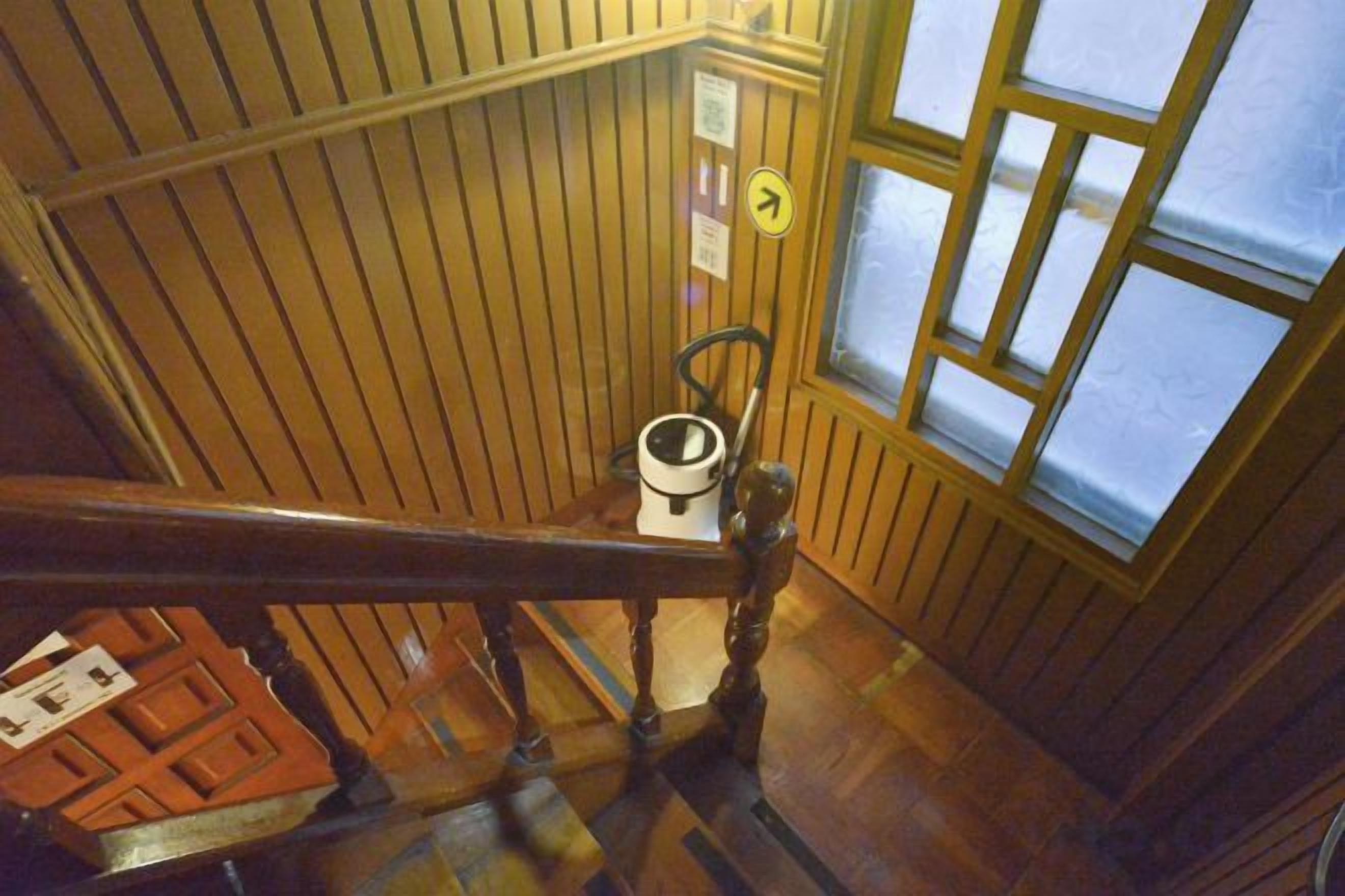 A wooden staircase with a handrail, a window with a view, and a wall-mounted sign.