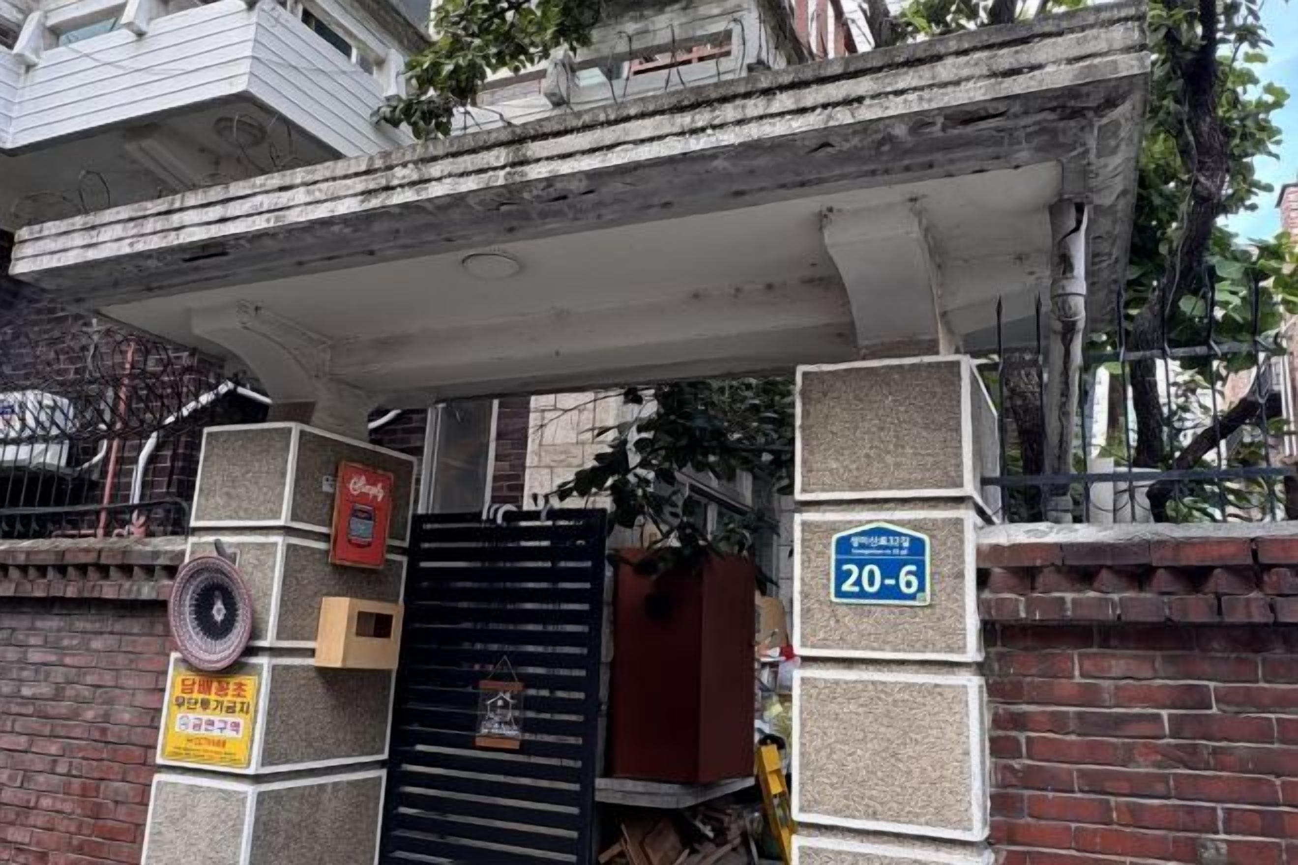 Una entrada tancada amb un senyal blau, una paret de maó i una estructura de formigó a la part superior.