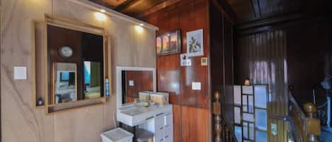 A wooden interior with a desk, chair, and a small trash bin.