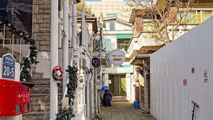 Une ruelle étroite avec une boîte aux lettres rouge, une pancarte indiquant « Bonjour le monde » et une couronne de Noël.