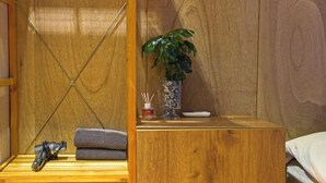 Une pièce en bois avec un lit, une petite table sur laquelle se trouve une plante, un vase et une télécommande.