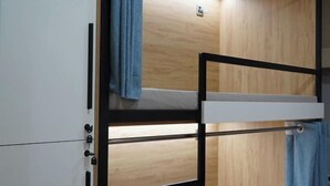 Una cama litera con escritorio abatible, paredes de madera y una lámpara.