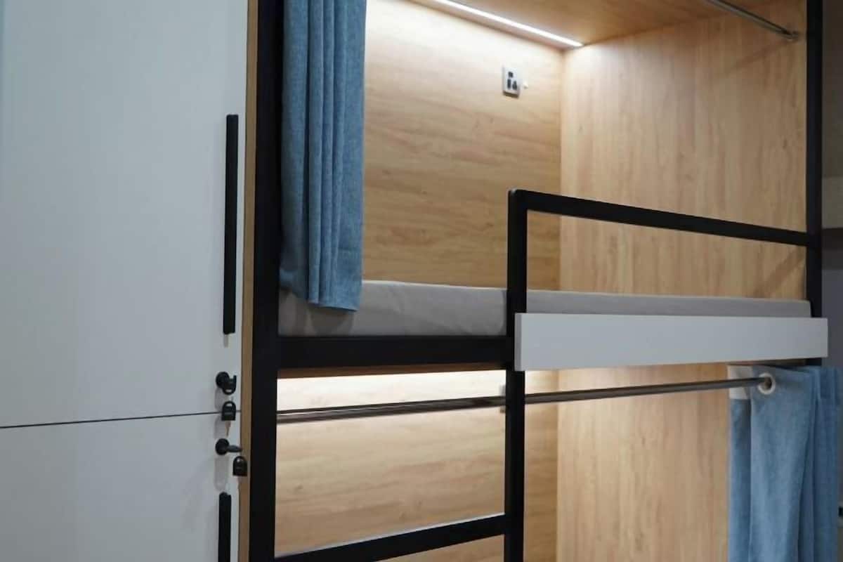 Een stapelbed met uitschuifbaar bureau, houten wanden en een lamp.