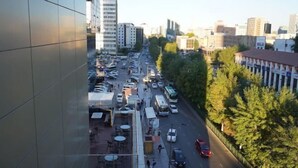 Una animada calle urbana con edificios, árboles y coches aparcados.