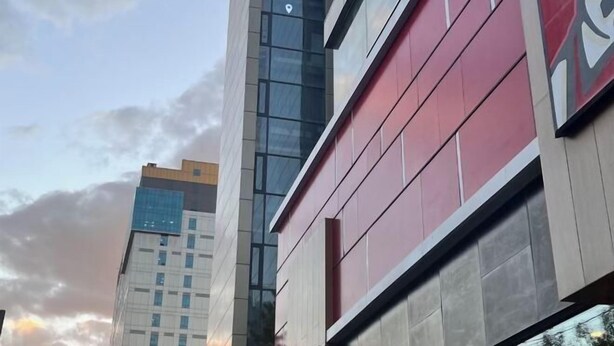 Un edificio moderno con fachada de vidrio y exterior en tonos rojo y gris.