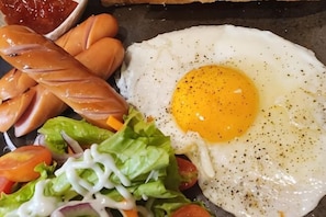 A breakfast plate with a fried egg, sausages, and a salad.