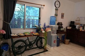 A kitchen with a bicycle, a water dispenser, and a clock on the wall.