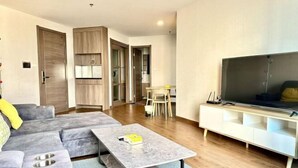 A modern living room with a sectional sofa, a coffee table, a flat-screen TV, and a dining area with a table and chairs. - Artisan Ratchada Apartment Bangkok, Thailand (Bangkok)