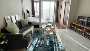A modern living room with a sofa, a coffee table, and a TV stand. - Artisan Ratchada Apartment Bangkok, Thailand (Bangkok)