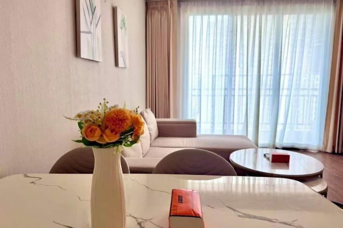 A room with a dining table, a vase with flowers, a sofa, and a round coffee table.