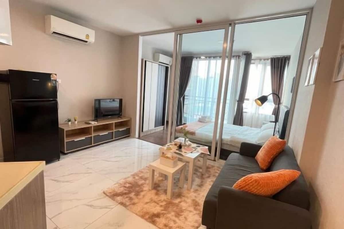 A modern living room with a sofa, a TV, a coffee table, and a sliding glass door leading to a balcony.
