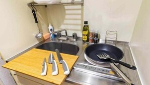Eine kleine Küche mit Spüle, Herd und Schneidebrett mit Messern.