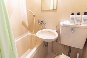 A bathroom with a white sink, a toilet, and a shower. There are three bottles of shampoo on the wall. - Tino Anastasia (Osaka)