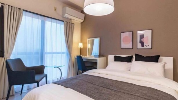 Ein Hotelzimmer mit Bett, Schreibtisch, Stuhl und einem großen Fenster.
