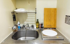 A compact kitchen with a stainless steel sink, a small countertop, and a wooden cabinet. - Tino Anastasia (Osaka)