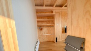 Ein Holzinnenraum mit integriertem Kleiderschrank, einem Heizkörper und einem Klappstuhl.