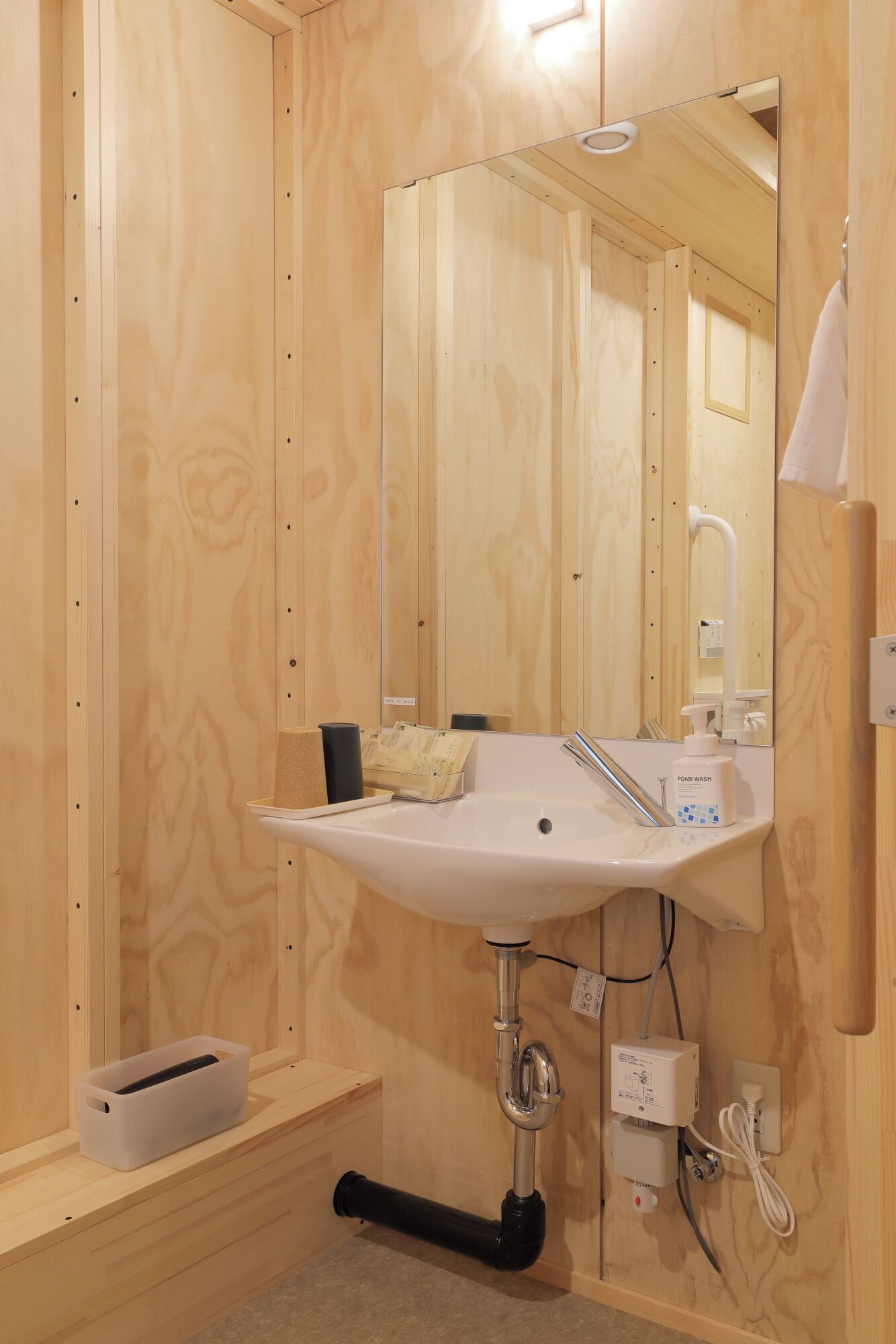 Un bagno in legno con lavandino bianco, specchio e asciugamano appeso al muro.
