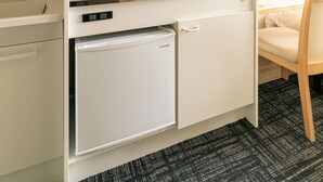 Eine kleine Küchenzeile mit Kühlschrank, Kaffeemaschine, Wasserkocher und Spüle.