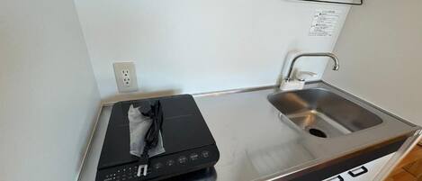 Una cocina compacta con estufa integrada, un lavamanos y una pequeña encimera.