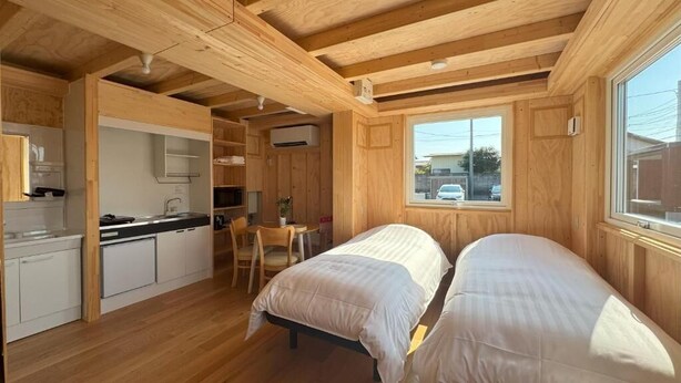 Ein gemütliches Blockhauszimmer mit zwei Betten, einer Küchenzeile und einem Essbereich.