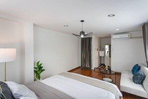 A hotel room with a bed, bedside table, lamp, and a seating area with a chair and cushions. - tropical private pool villa (Bangkok)
