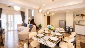 A modern dining area with a marble table, white chairs, and pendant lighting. - tropical private pool villa (Bangkok)