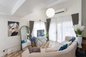 A modern living room with a sofa, a flat-screen TV, and a large mirror. - tropical private pool villa (Bangkok)