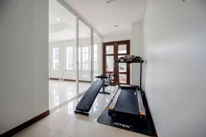 A gym with treadmills and exercise equipment, large windows, and a sliding glass door. - tropical private pool villa (Bangkok)