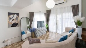 A modern living room with a beige sofa, a marble coffee table, and a large mirror. - tropical private pool villa (Bangkok)