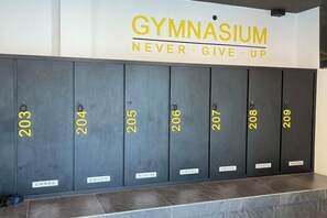 Una hilera de casilleros con los números del 203 al 209, y un letrero encima que dice 'GYMNASIUM NUNCA TE RINDAS'.