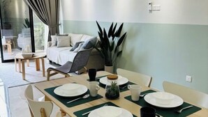 Un comedor con una mesa dispuesta para cuatro personas, un sofá y una planta grande.