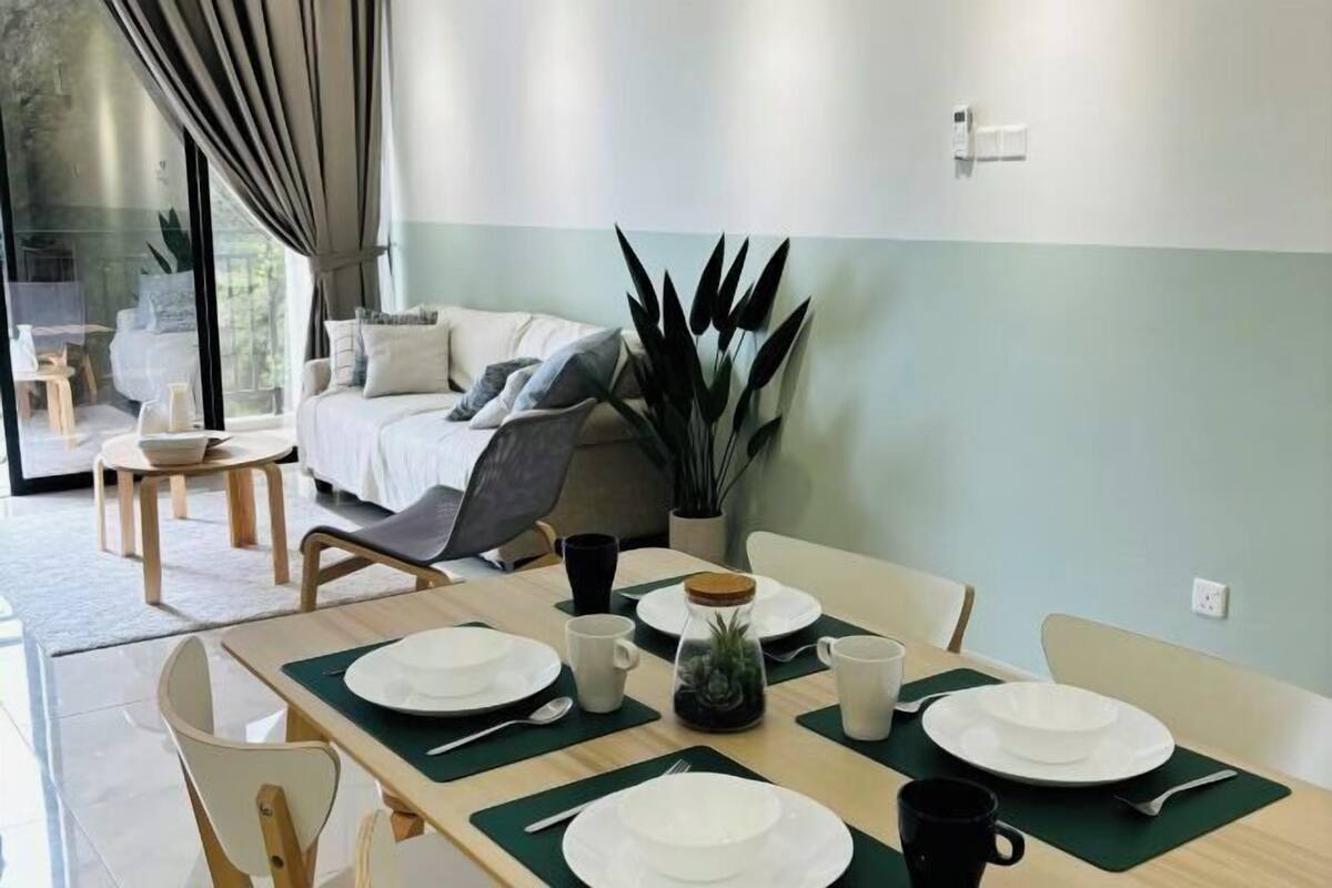 Un comedor con una mesa dispuesta para cuatro personas, un sofá y una planta grande.