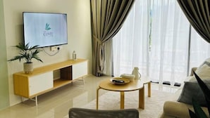 Una sala de estar moderna con un televisor de pantalla plana, un mueble bajo de madera, una mesa redonda de centro y un sofá.