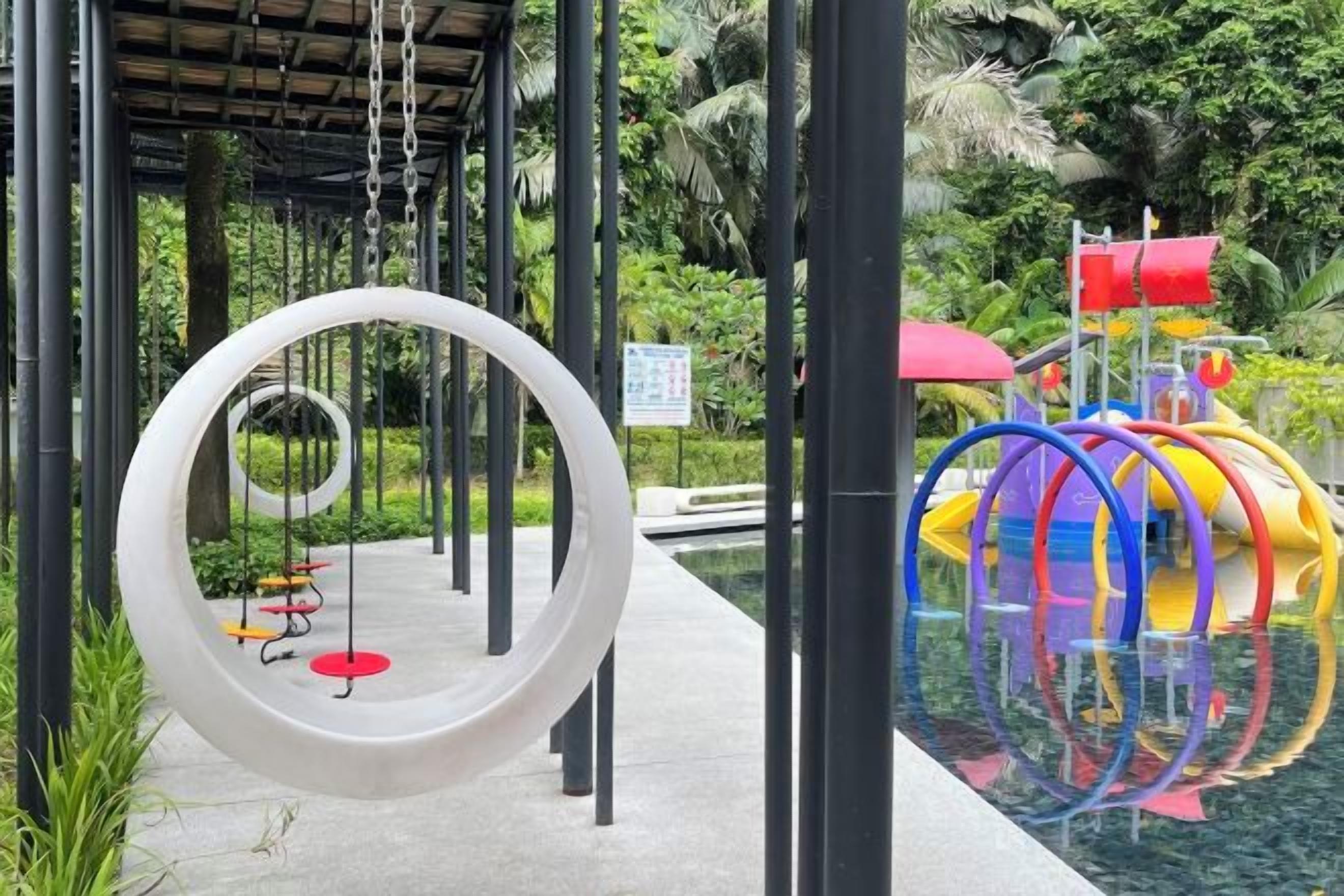 A playground with a circular swing, a water slide, and a covered area with benches.