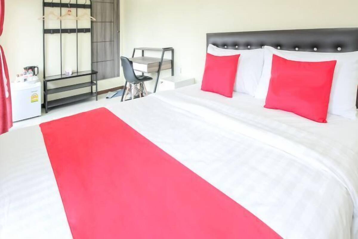 A hotel room with a large bed, a desk, and a chair.