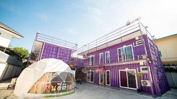 A multi-story building with a purple exterior, a covered area with a transparent roof, and a visible entrance.