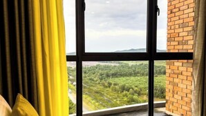 Ein Zimmer mit großem Fenster, Ziegelwand und gelben Vorhängen.